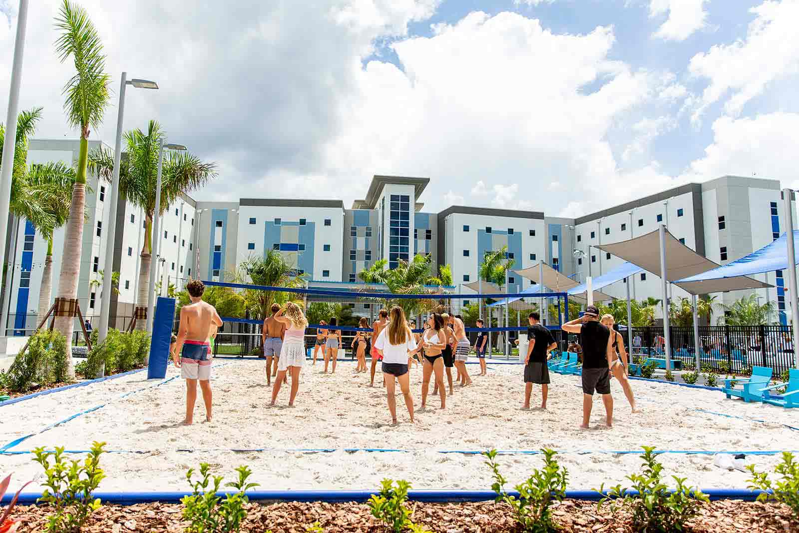 Students enjoying beach volleyball on the IMG Academy campus with residence halls in the background